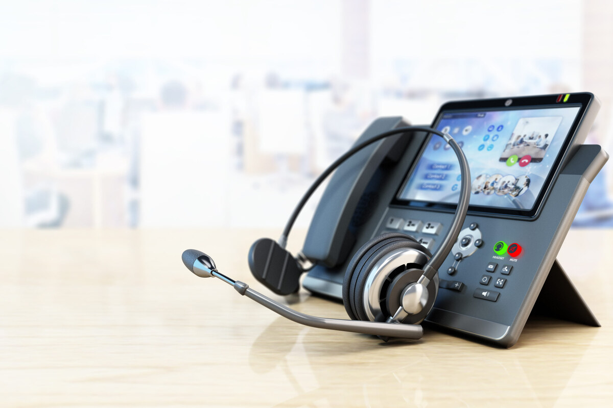 A headset resting beside a business desk phone.