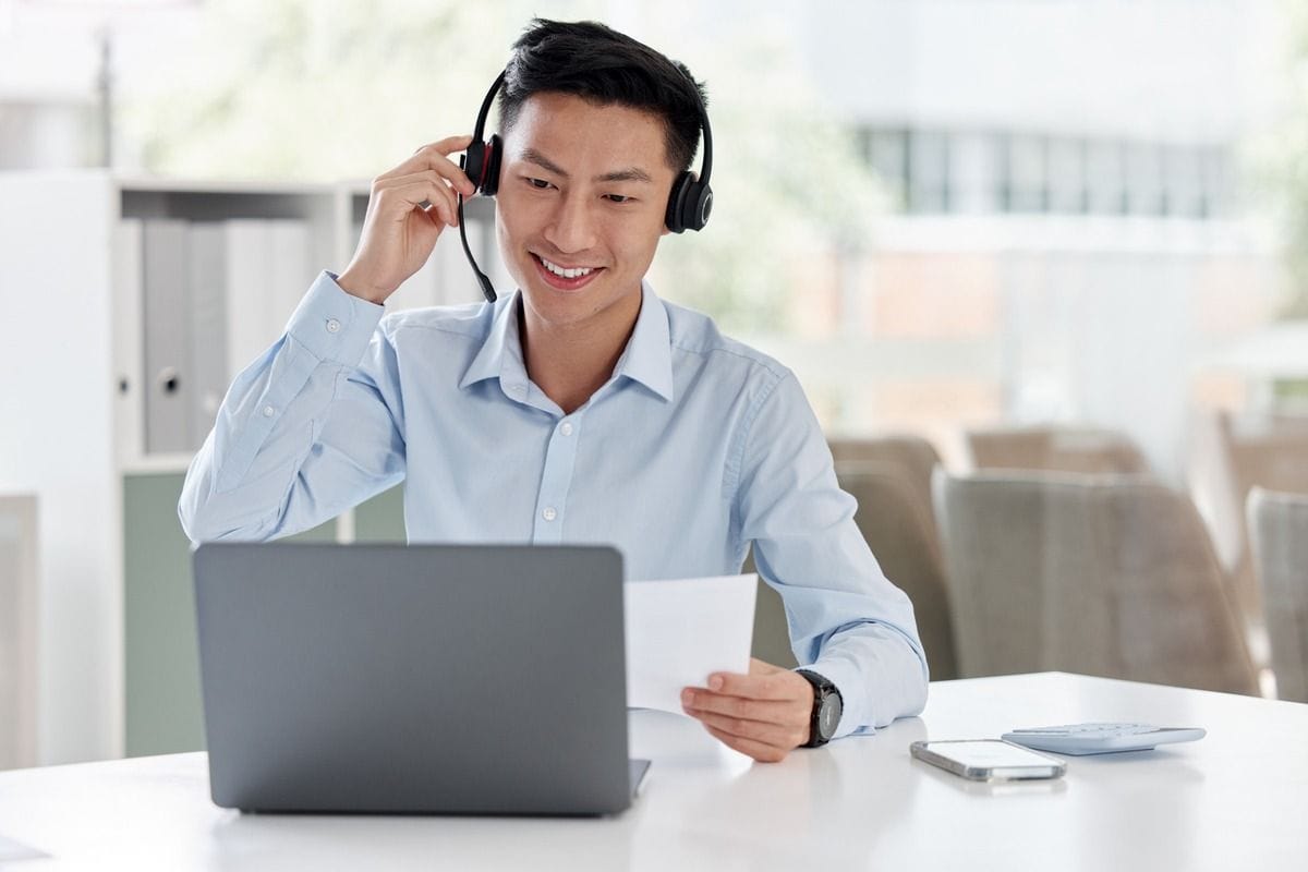 An employee answers a call with a headset and laptop.