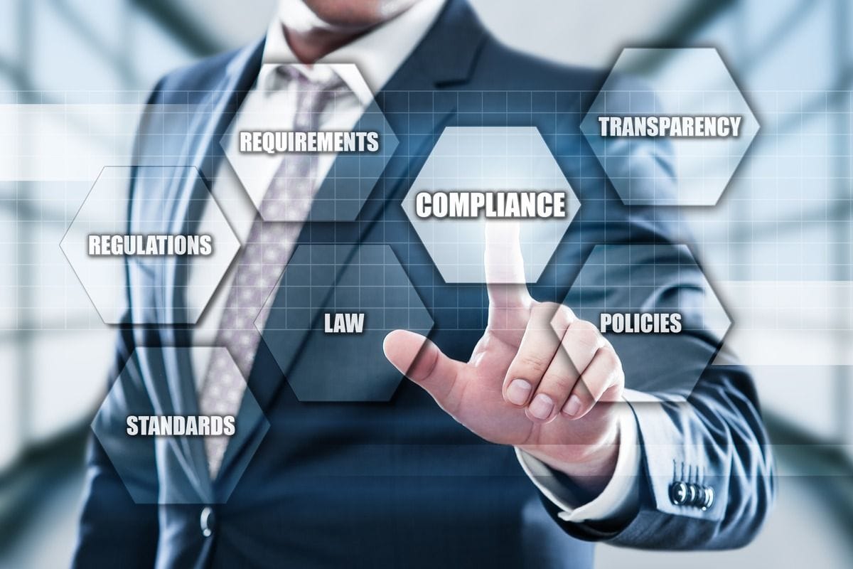 A businessman in a suit touches a screen of compliance terms.