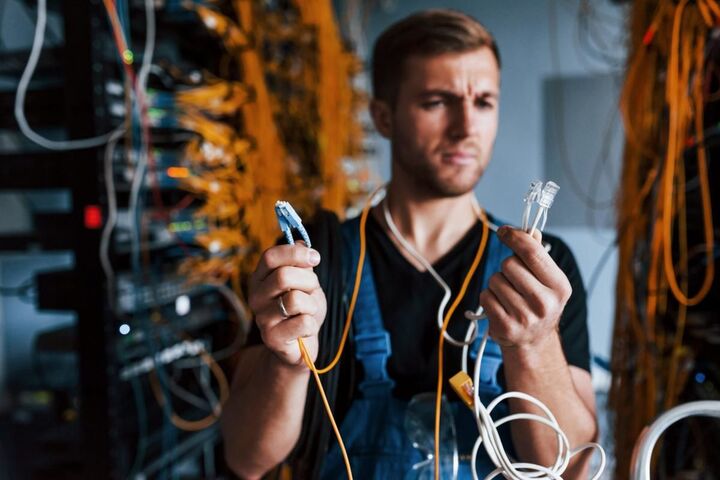 A technician testing a network cable in a wiring room.
