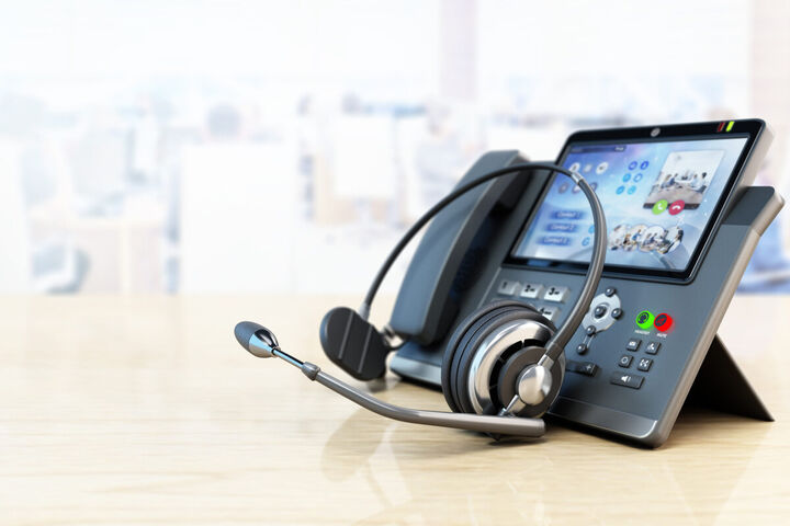 A headset resting beside a business desk phone.