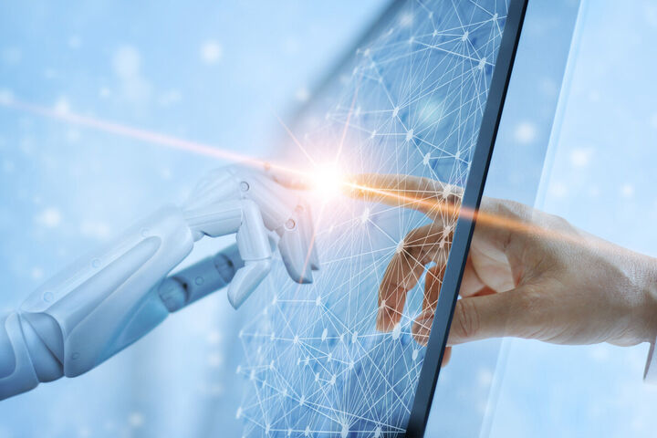 A robot hand and a human hand meet on a glowing network screen.