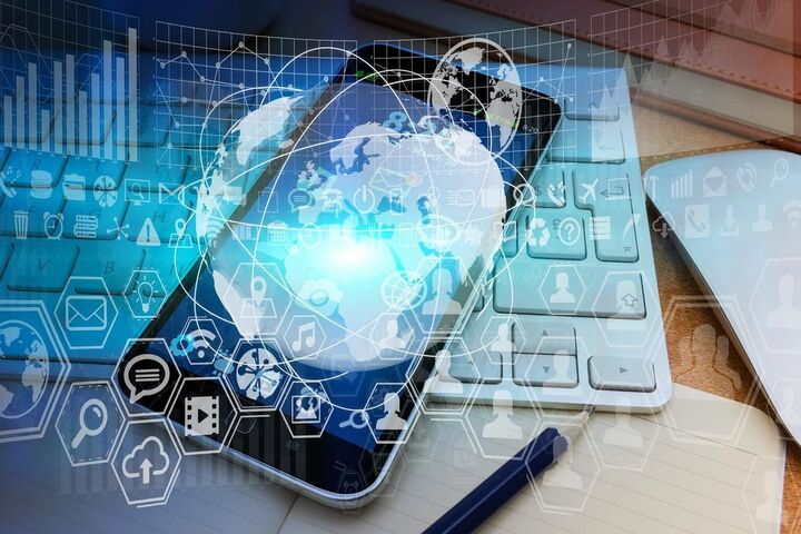 A phone and a laptop beside printed charts.