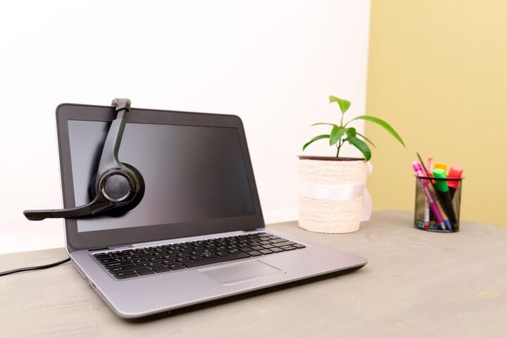 A computer on a desk with a keyboard and a small plant.