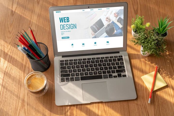 A laptop showing a website template on a wooden desk.