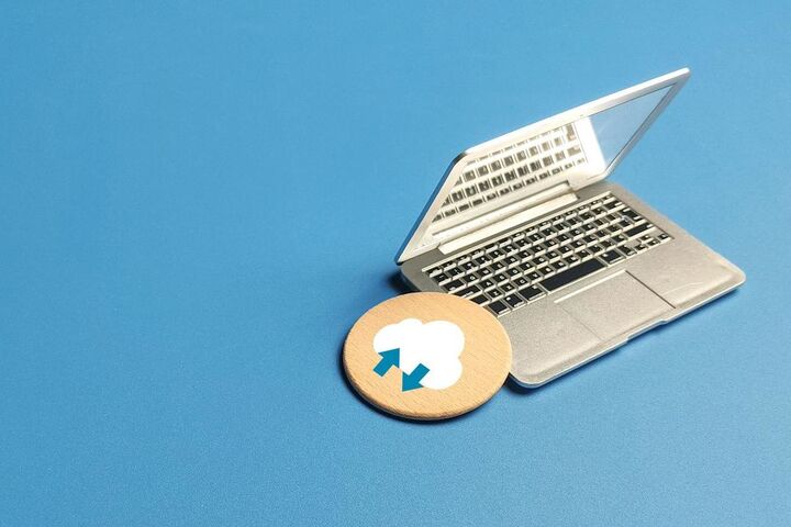 A white cloud floating above a laptop on a desk.
