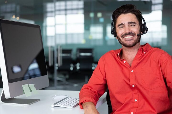 A smiling businessman wearing a headset at his desk.