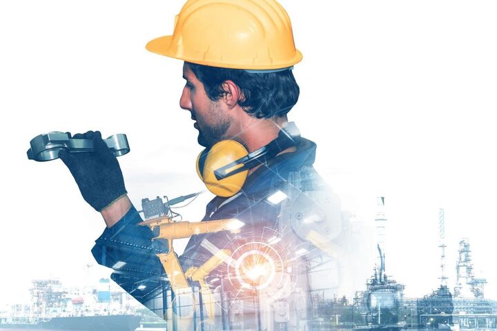 A worker in a hard hat beside industrial robots.