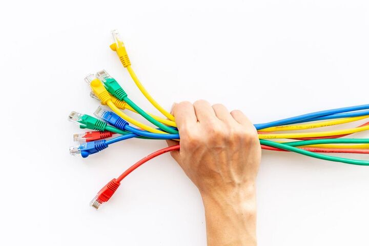 A hand holding a bundle of coloured network cables.