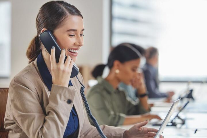 Two colleagues at a desk, one wearing a headset.