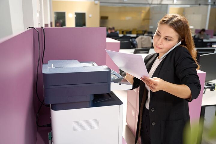 A woman reading a document at a filing cabinet.