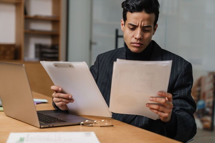 A man concentrating at his desk in a busy office.