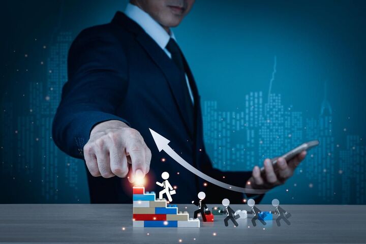 Tiny figures climb a bar chart staircase while a businessman points upward.