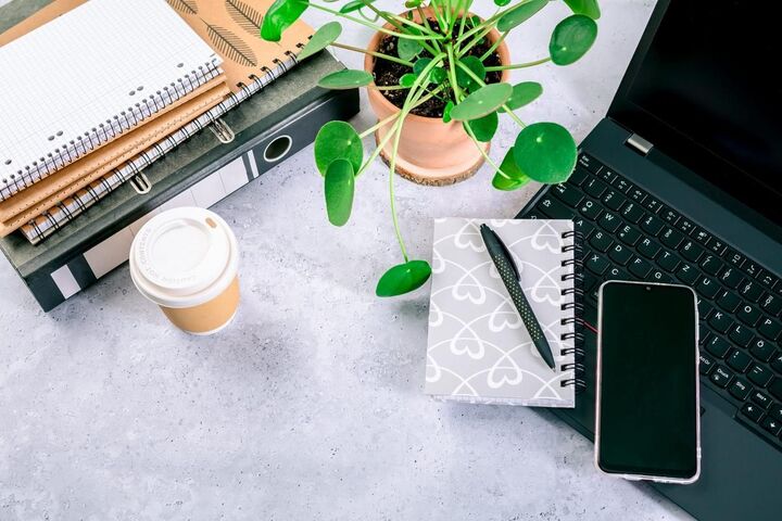 A tidy desk with a laptop, notebook and coffee.