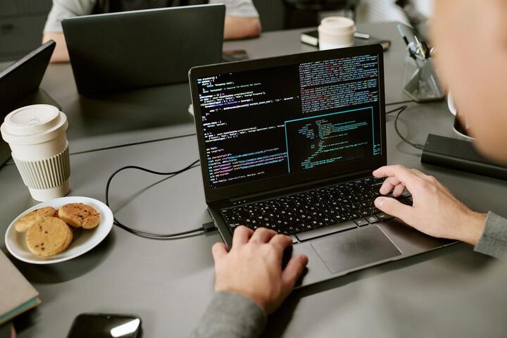 Two people working on code at laptops in an office.
