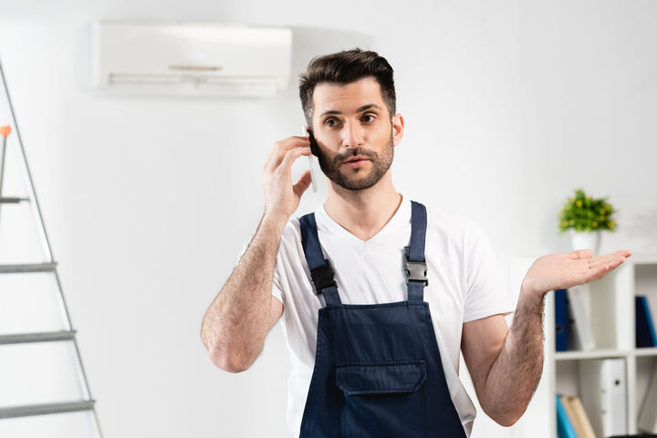 A repair technician holding a tool in front of a machine.