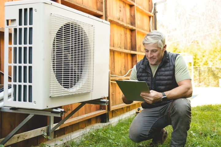 An engineer servicing an air conditioning unit outdoors.