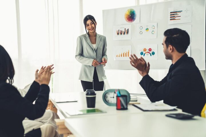 A woman presenting to colleagues in a meeting room.